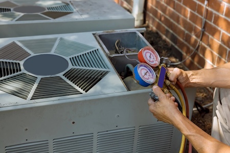 HVAC technician inspecting an outdoor AC condenser in Auburn, KS